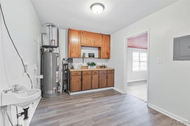 kitchen featuring electric panel, sink, light hardwood / wood-style flooring, and gas water heater