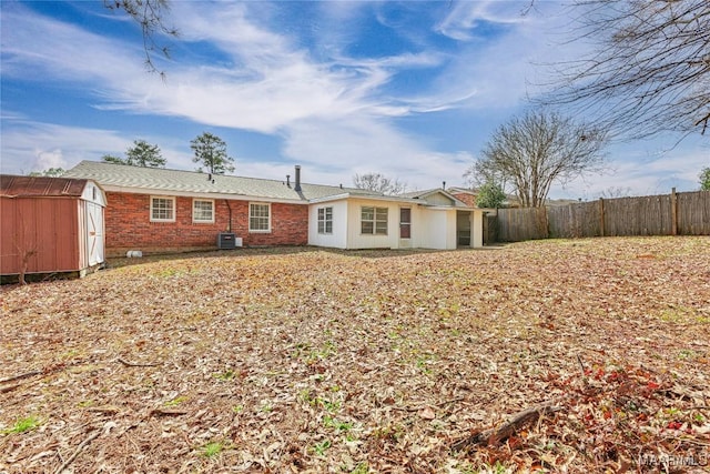 rear view of property with cooling unit and a shed