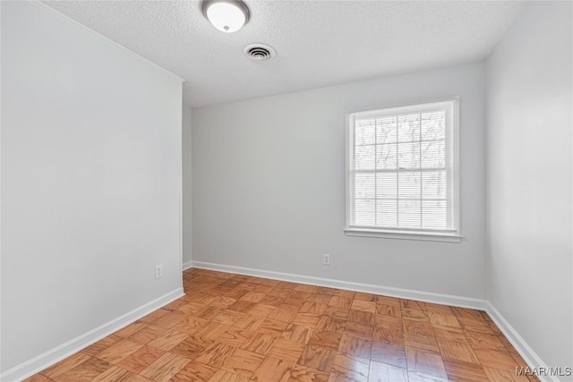 spare room with a textured ceiling and light parquet flooring