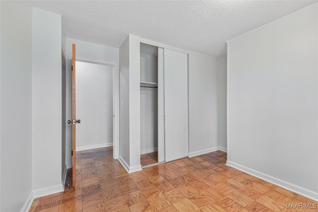 unfurnished bedroom featuring light parquet floors, a closet, and a textured ceiling