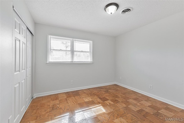 unfurnished bedroom with parquet flooring, a textured ceiling, and a closet