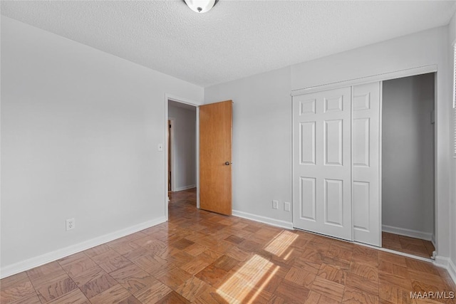 unfurnished bedroom with light parquet floors, a textured ceiling, and a closet