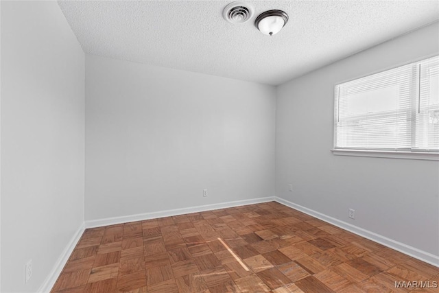 spare room with parquet flooring and a textured ceiling