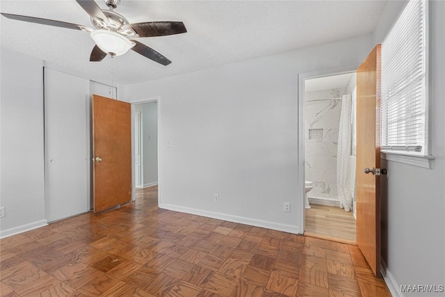 unfurnished bedroom featuring ceiling fan, parquet flooring, connected bathroom, and a textured ceiling