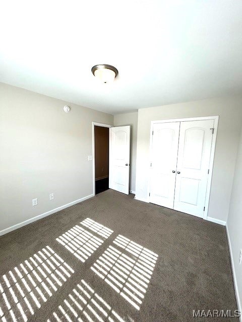 unfurnished bedroom featuring dark carpet and a closet