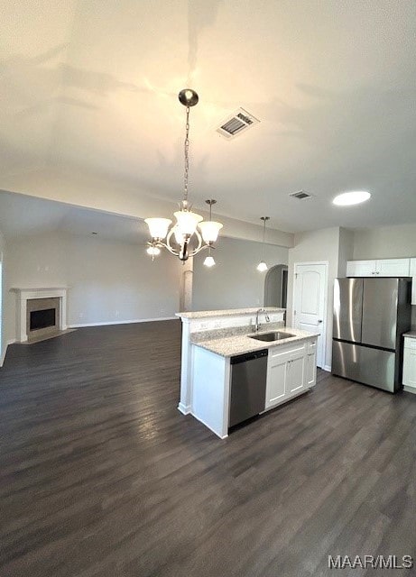 kitchen with sink, decorative light fixtures, appliances with stainless steel finishes, a kitchen island with sink, and white cabinets