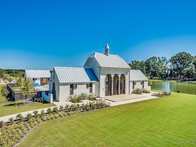 back of house featuring a water view and a lawn