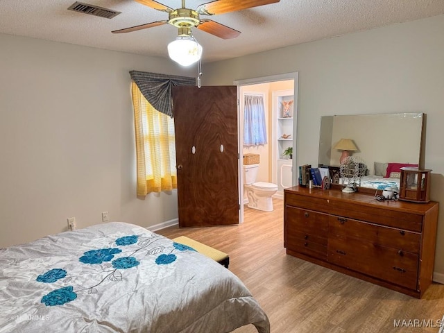 bedroom featuring ceiling fan, connected bathroom, light hardwood / wood-style flooring, and a textured ceiling