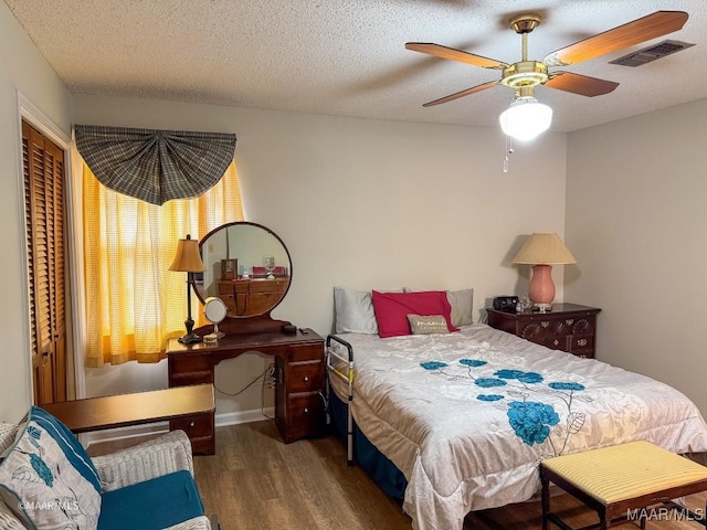 bedroom with dark wood-type flooring, ceiling fan, and a textured ceiling