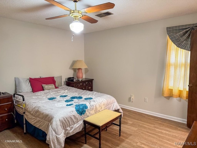 bedroom with hardwood / wood-style flooring, ceiling fan, and a textured ceiling