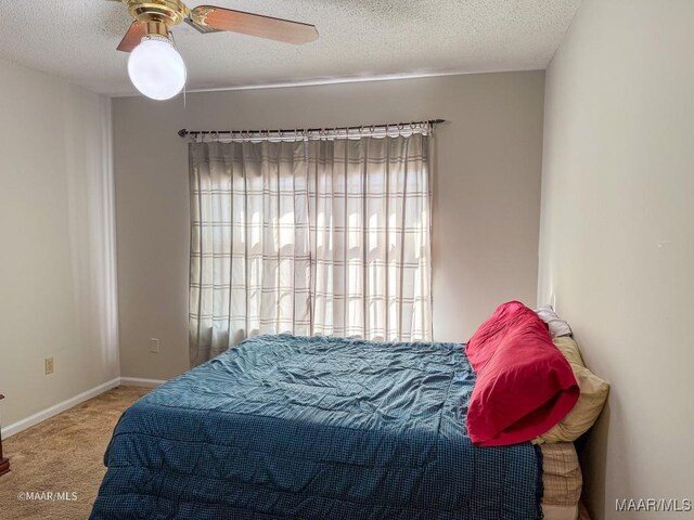 bedroom with ceiling fan, carpet, and a textured ceiling