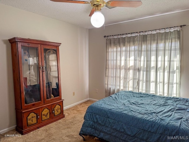 bedroom with ceiling fan, light colored carpet, and a textured ceiling