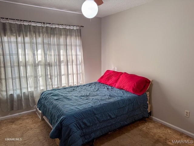 carpeted bedroom featuring ceiling fan and a textured ceiling