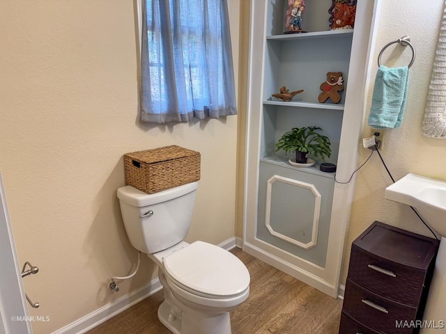 bathroom featuring wood-type flooring and toilet