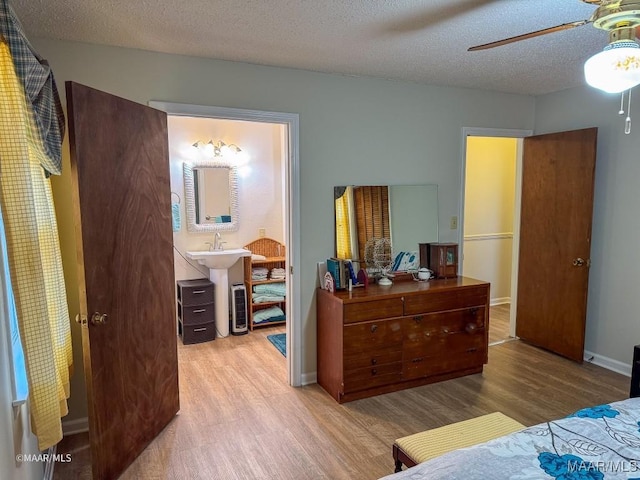 bedroom with ceiling fan, light hardwood / wood-style flooring, sink, and a textured ceiling