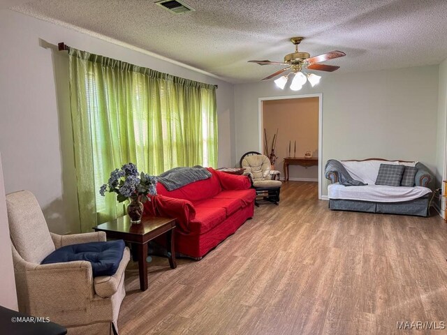 living room featuring a textured ceiling, ceiling fan, and light hardwood / wood-style flooring