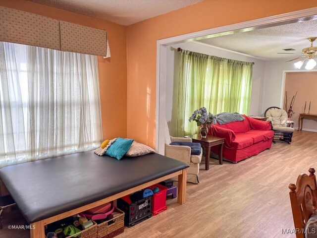 recreation room with hardwood / wood-style floors, a textured ceiling, a healthy amount of sunlight, and ceiling fan