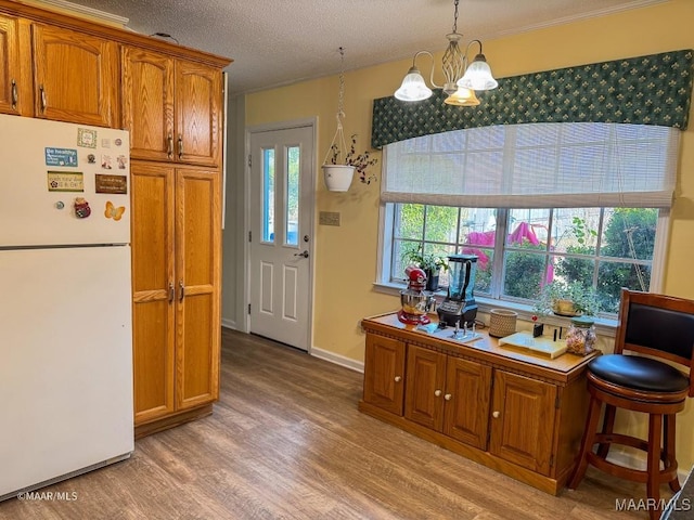 kitchen featuring decorative light fixtures, white fridge, a notable chandelier, a textured ceiling, and light hardwood / wood-style flooring