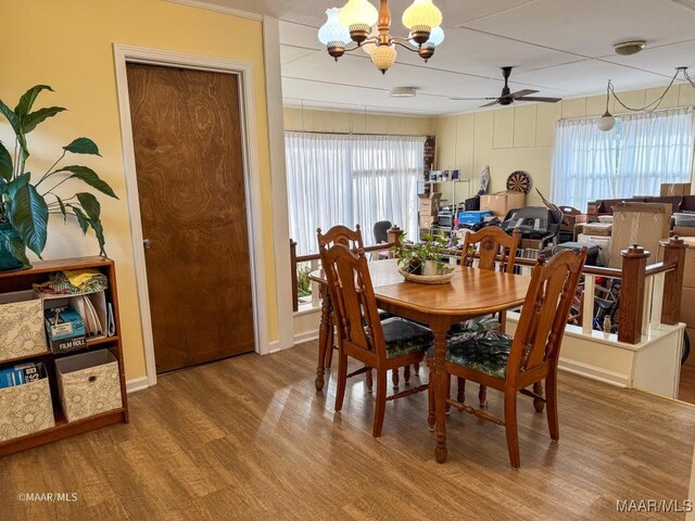 dining area featuring ceiling fan with notable chandelier and hardwood / wood-style floors