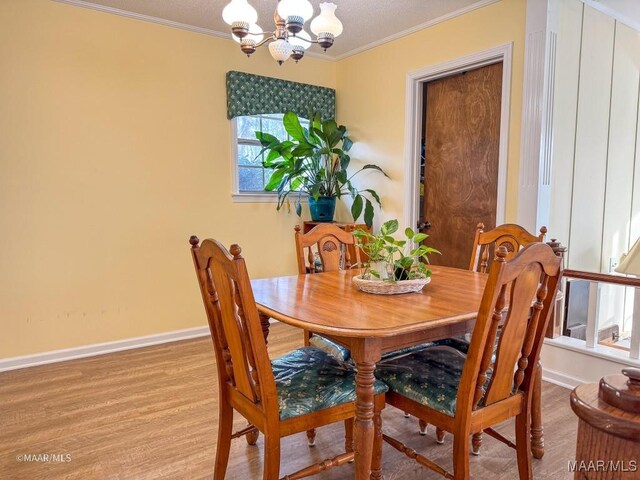 dining space with crown molding, a notable chandelier, and light wood-type flooring