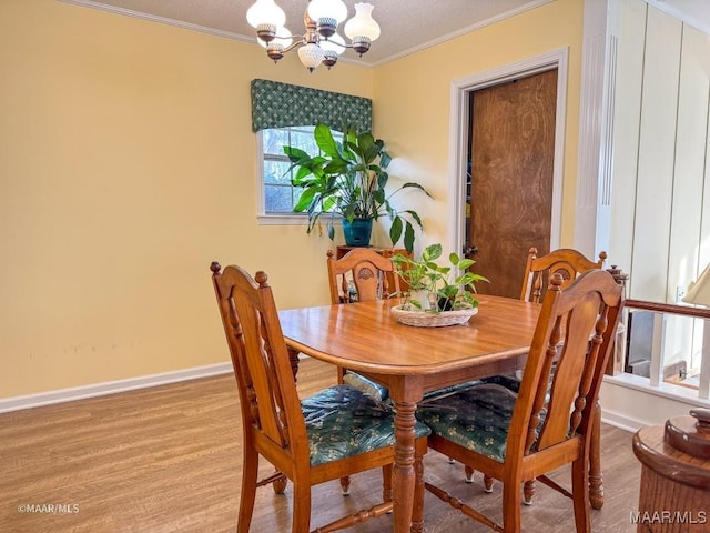 dining area featuring crown molding, light hardwood / wood-style flooring, and a notable chandelier