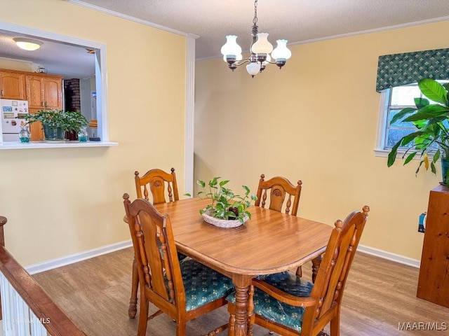 dining space featuring an inviting chandelier, crown molding, and light hardwood / wood-style flooring