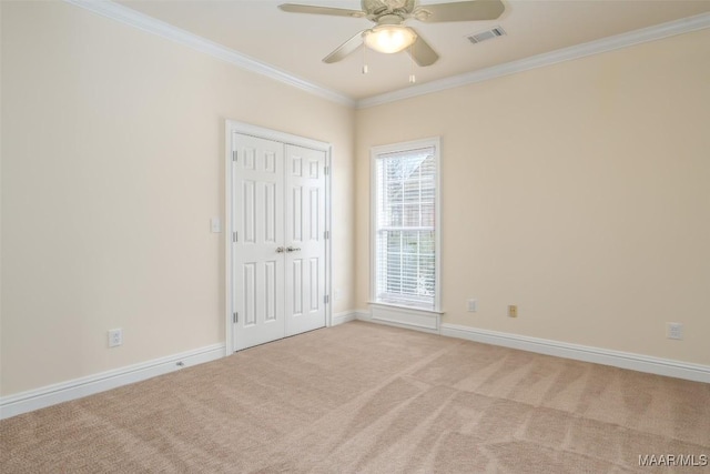 empty room with ceiling fan, ornamental molding, and light carpet