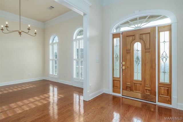 foyer with crown molding, a notable chandelier, and hardwood / wood-style flooring