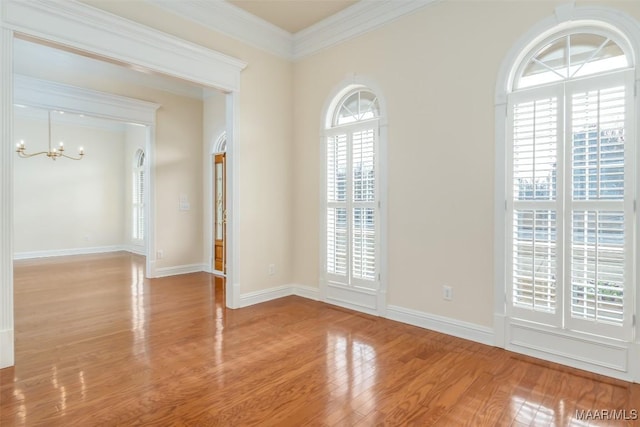 empty room with an inviting chandelier, crown molding, and hardwood / wood-style flooring