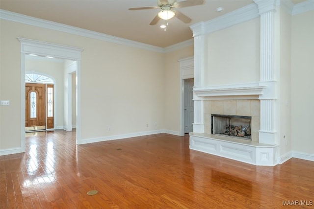 unfurnished living room featuring hardwood / wood-style flooring, a tile fireplace, ceiling fan, and crown molding