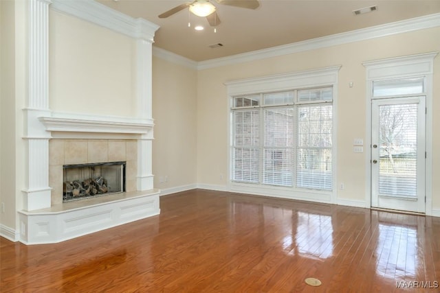 unfurnished living room with a tiled fireplace, wood-type flooring, ceiling fan, and crown molding