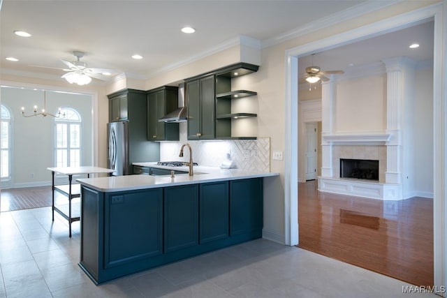 kitchen featuring wall chimney exhaust hood, stainless steel fridge, kitchen peninsula, and sink