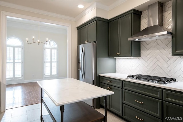 kitchen featuring wall chimney exhaust hood, hanging light fixtures, appliances with stainless steel finishes, ornamental molding, and backsplash