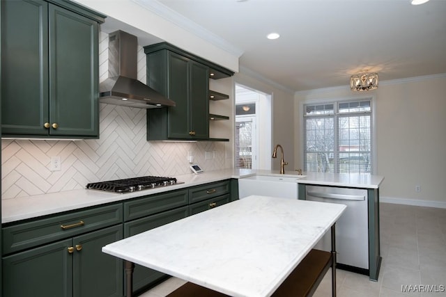 kitchen featuring sink, crown molding, green cabinets, appliances with stainless steel finishes, and wall chimney exhaust hood