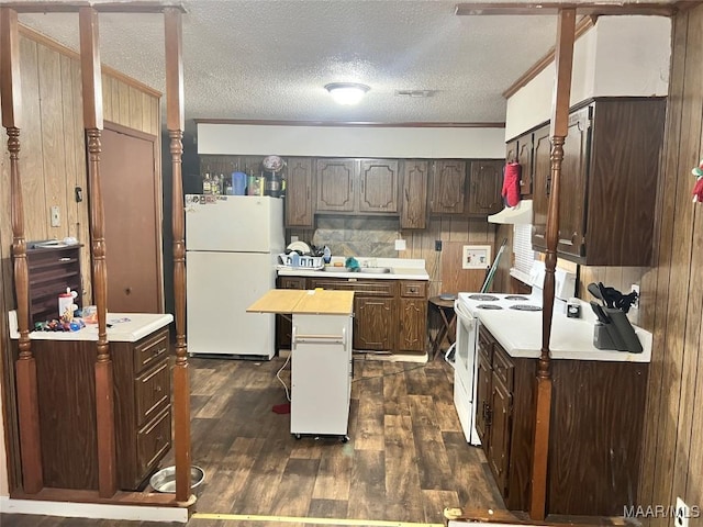 kitchen with dark brown cabinetry, a textured ceiling, dark hardwood / wood-style flooring, a kitchen island, and white appliances