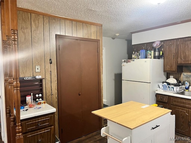 kitchen with white refrigerator, wooden walls, and a textured ceiling