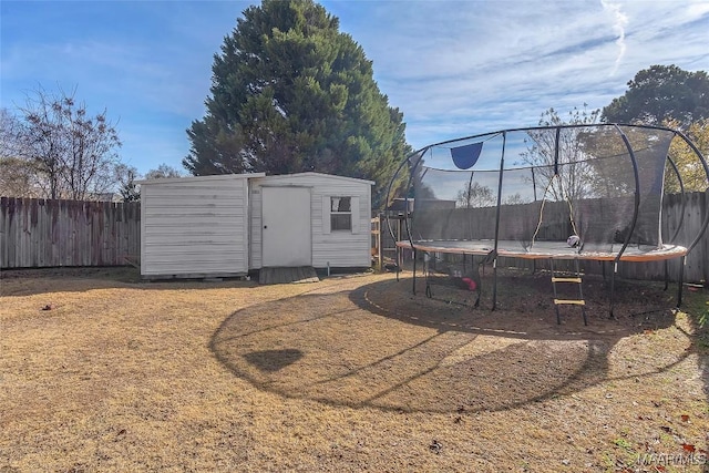 view of yard featuring a trampoline and a storage unit