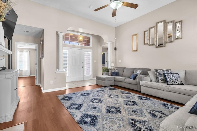 living room featuring decorative columns, dark hardwood / wood-style floors, and ceiling fan