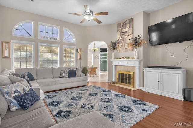 living room with hardwood / wood-style floors, ceiling fan with notable chandelier, and a tile fireplace