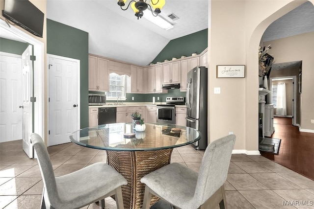 dining room featuring vaulted ceiling, sink, and light tile patterned floors