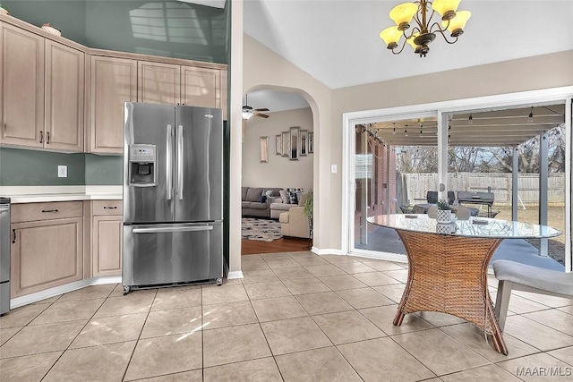 kitchen with stainless steel refrigerator with ice dispenser, light tile patterned flooring, ceiling fan with notable chandelier, vaulted ceiling, and light brown cabinets