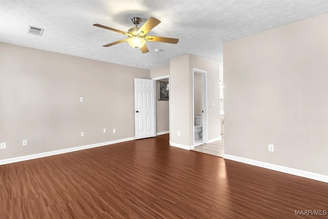 empty room with ceiling fan, wood-type flooring, and a textured ceiling