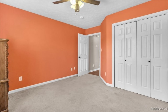 unfurnished bedroom with ceiling fan, light colored carpet, a closet, and a textured ceiling