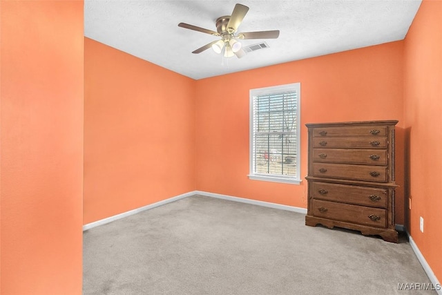 empty room featuring ceiling fan, light carpet, and a textured ceiling