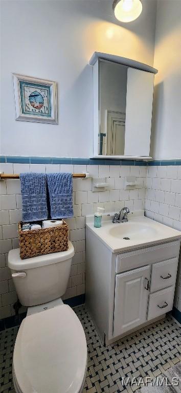 bathroom with tile patterned flooring, vanity, tile walls, and toilet