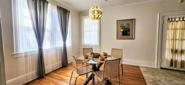 dining area with an inviting chandelier, ornamental molding, and light hardwood / wood-style flooring