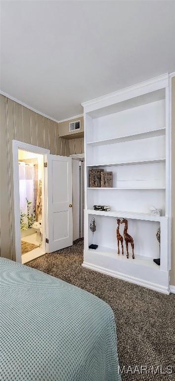 carpeted bedroom featuring crown molding and wooden walls