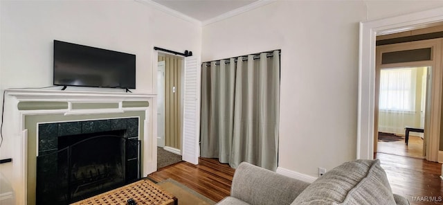 living room featuring hardwood / wood-style flooring, ornamental molding, and a barn door