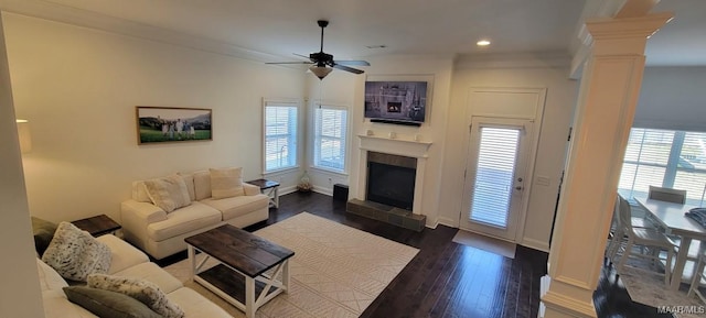 living room with a wealth of natural light, dark wood-type flooring, and decorative columns