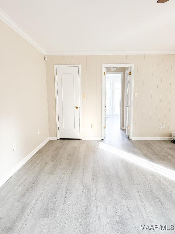 unfurnished room with ornamental molding and light wood-type flooring